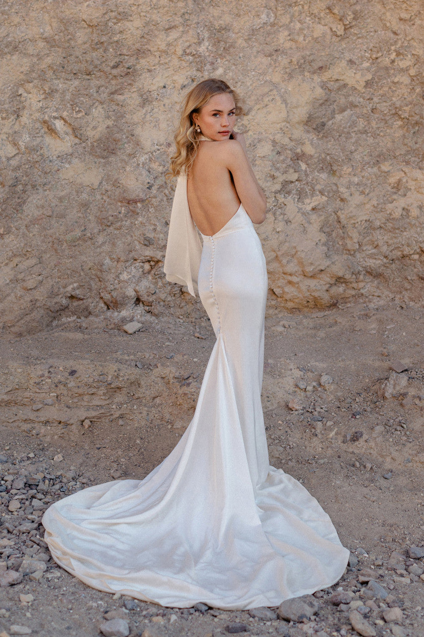 Victoria is a high-neck halter gown in liquid satin that drapes with quiet luxury.