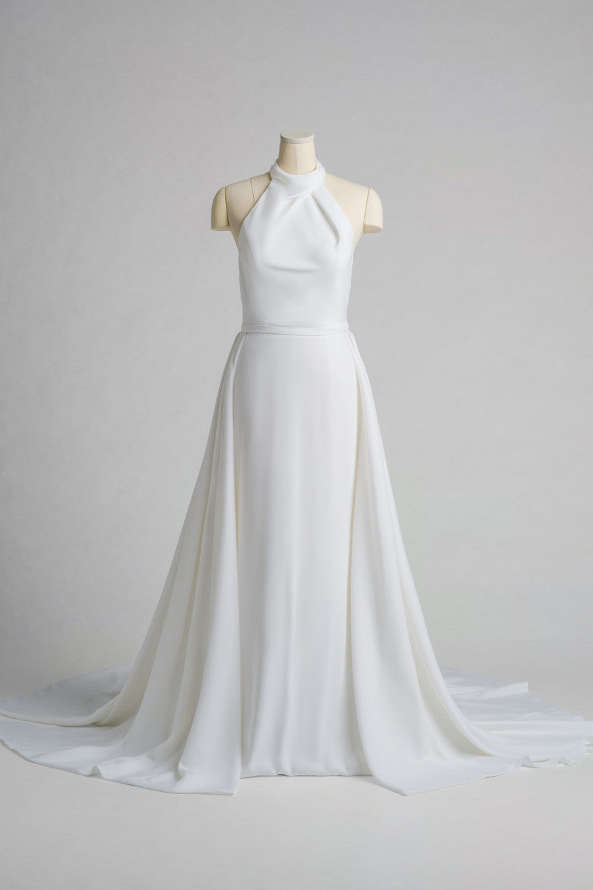Victoria is a high-neck halter gown in liquid satin that drapes with quiet luxury.